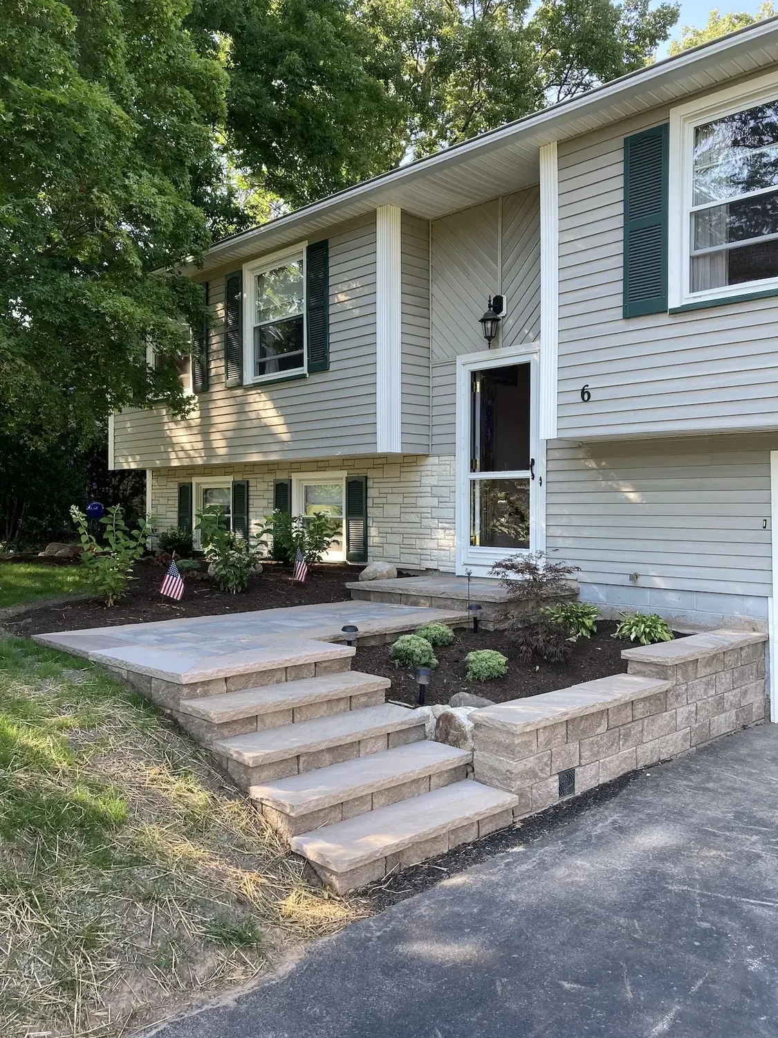 Second completed view of the paver front entry from the driveway, showing broad steps and the low wall